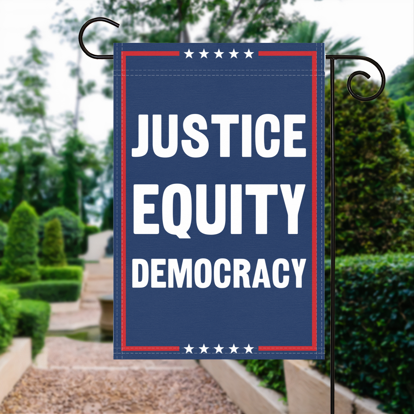 A red, white and blue political garden flag with the slogan Justice Equity Democracy.