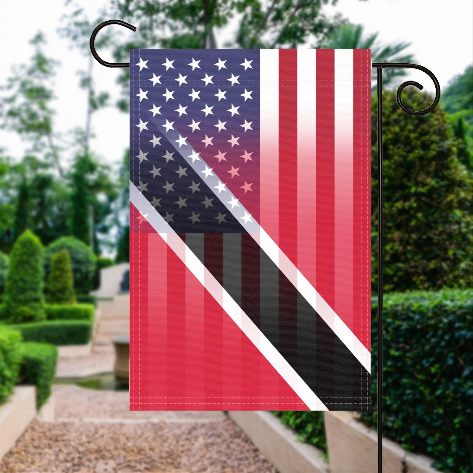 A garden flag with the Trini American flag design seamlessly blended with the American flag, displayed in a garden.