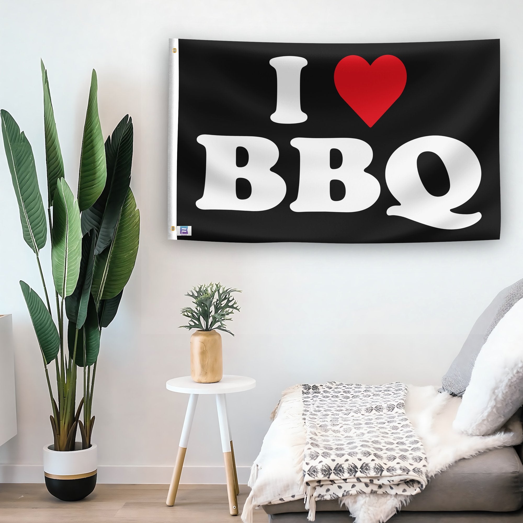 In a home setting, a flag with the saying "I Love BBQ" is mounted on a white wall by a side table.