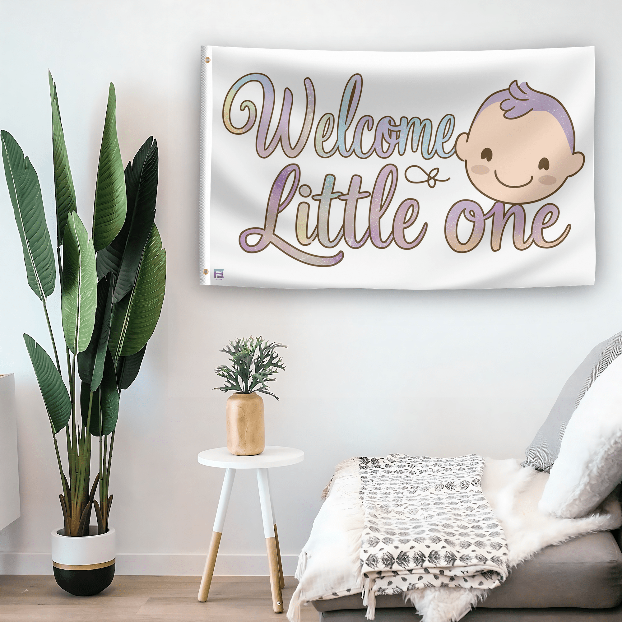 In a home setting, a flag with the saying "Welcome Little One" is mounted on a white wall by a side table.