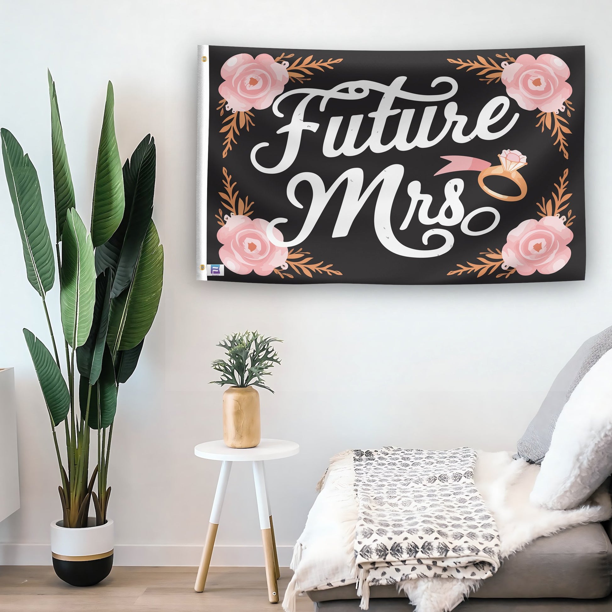 In a home setting, a flag with the saying "Future Mrs" is mounted on a white wall by a side table.