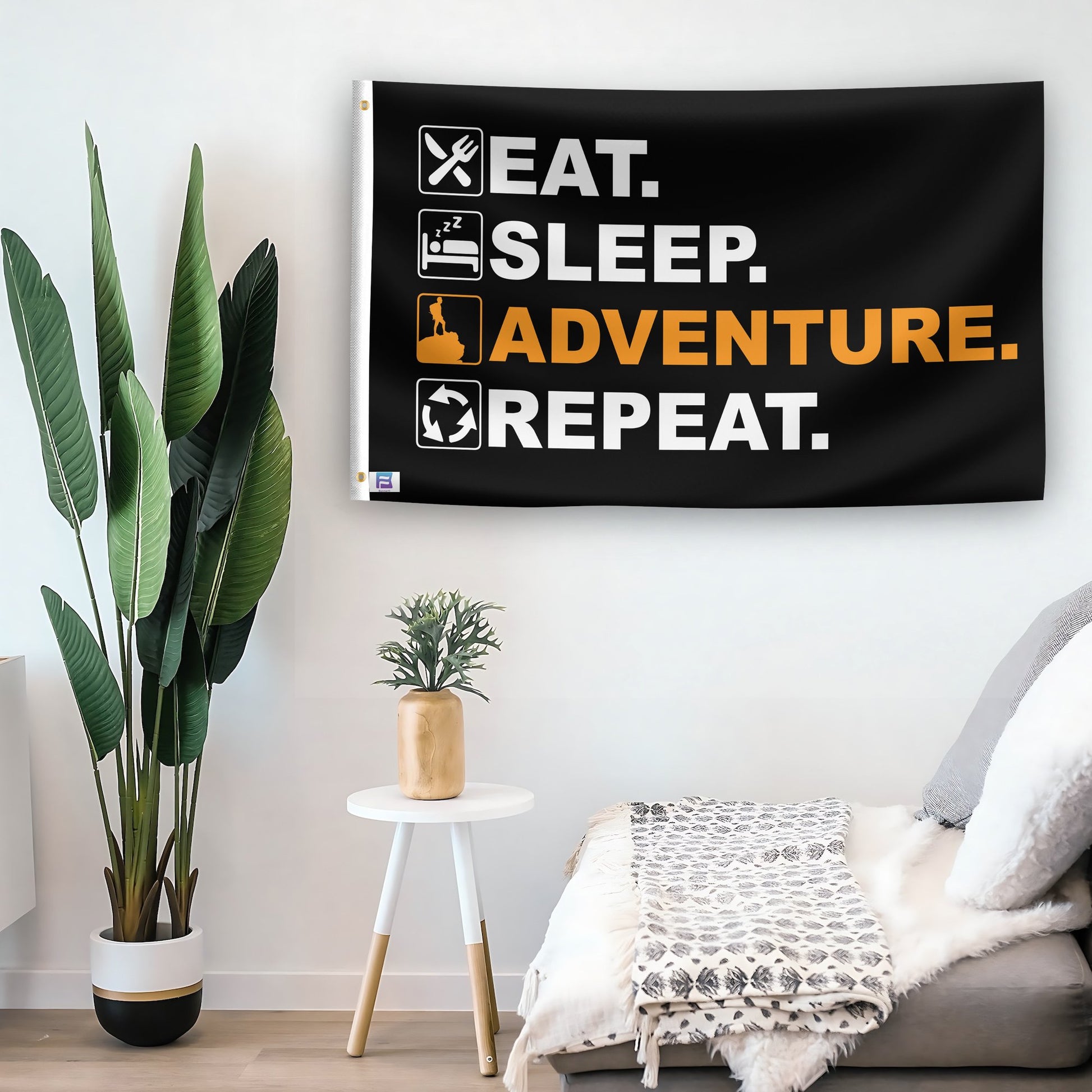 In a home setting, a flag with the saying "Eat Sleep Adventure Repeat" is mounted on a white wall by a side table.