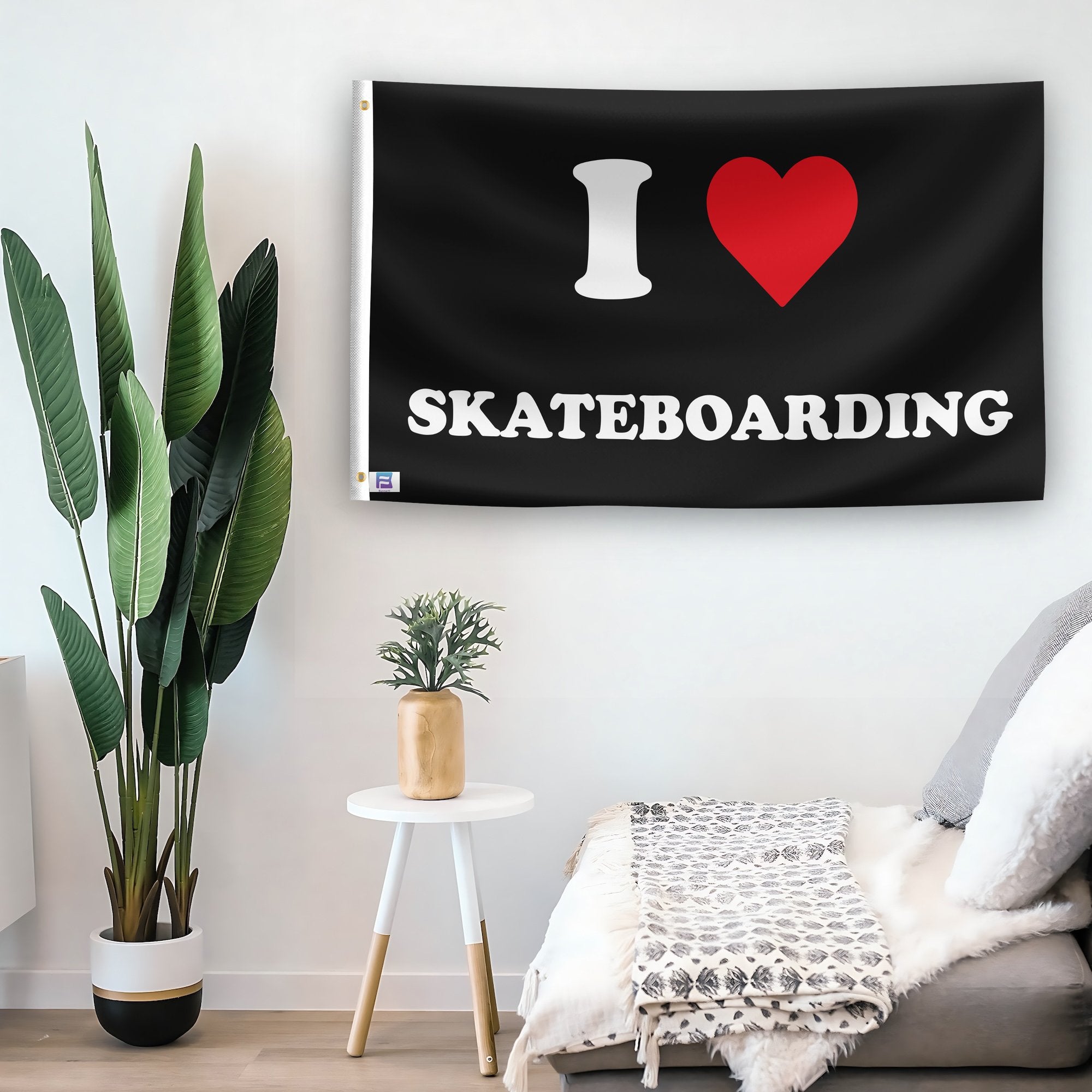 In a home setting, a flag with the saying "I Love Skateboarding" is mounted on a white wall by a side table.