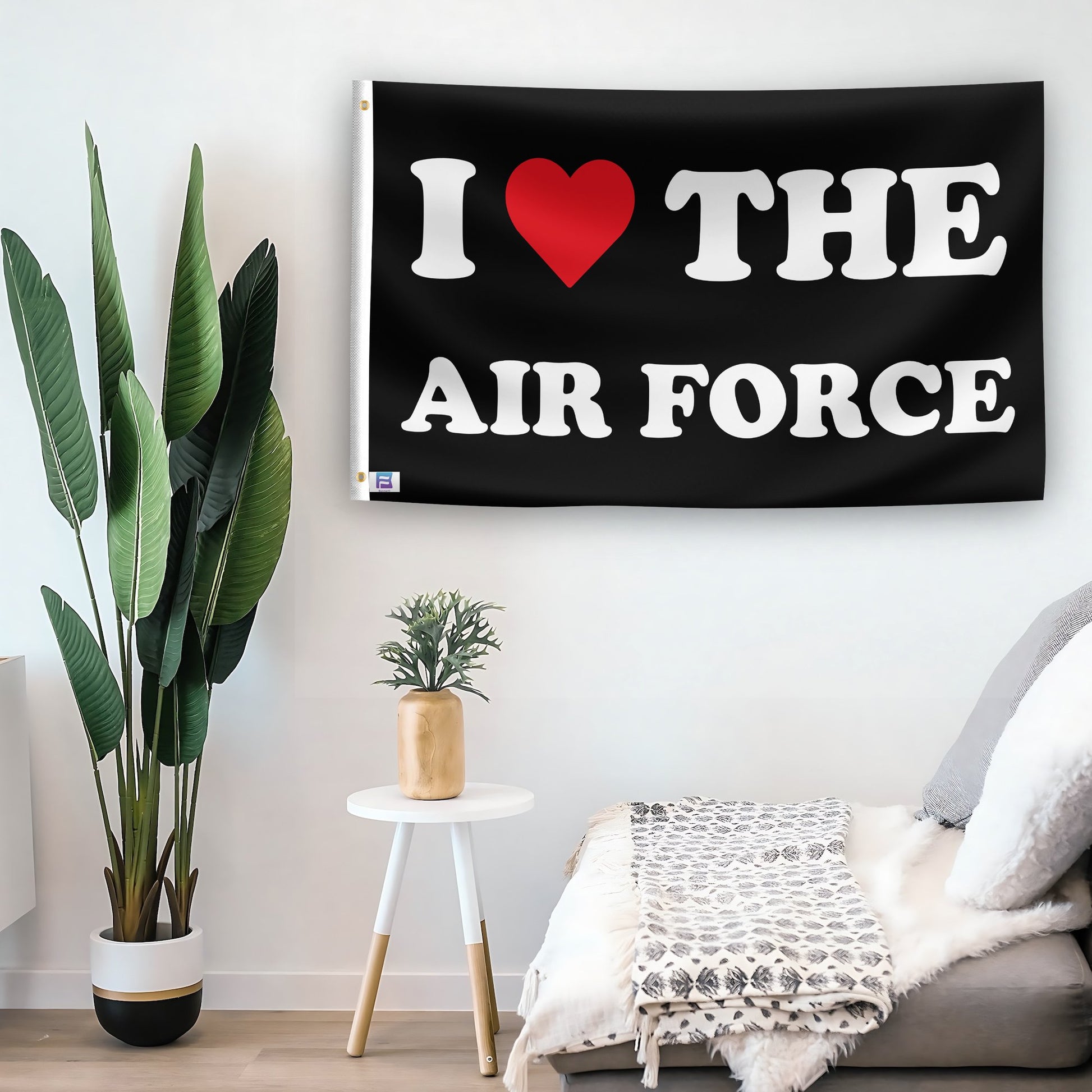 In a home setting, a flag with the saying "I Love The Air Force" is mounted on a white wall by a side table.