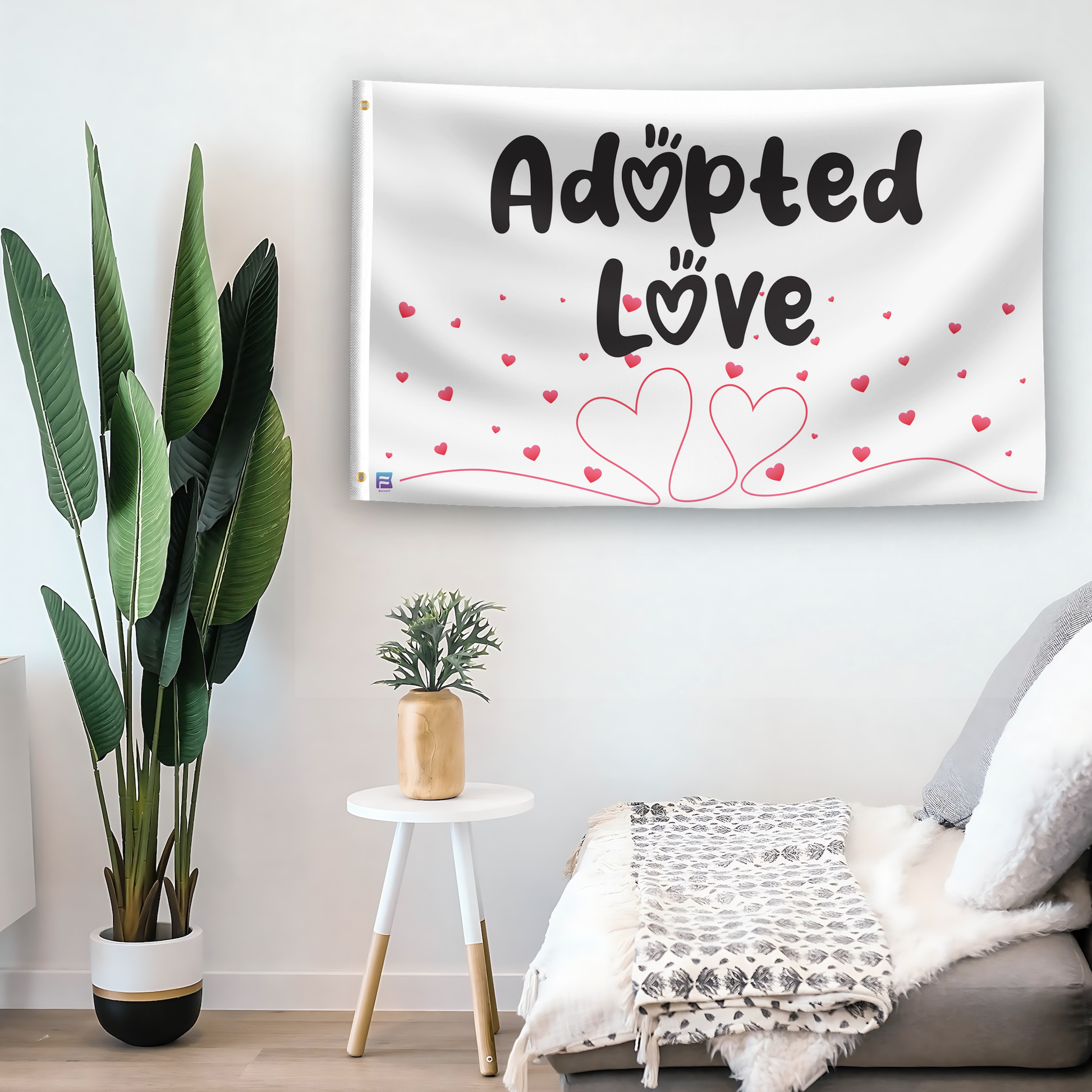 In a home setting, a flag with the saying "Adopted Love" is mounted on a white wall by a side table.