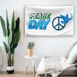 In a home setting, a flag with the saying "Peace Day" is mounted on a white wall by a side table.