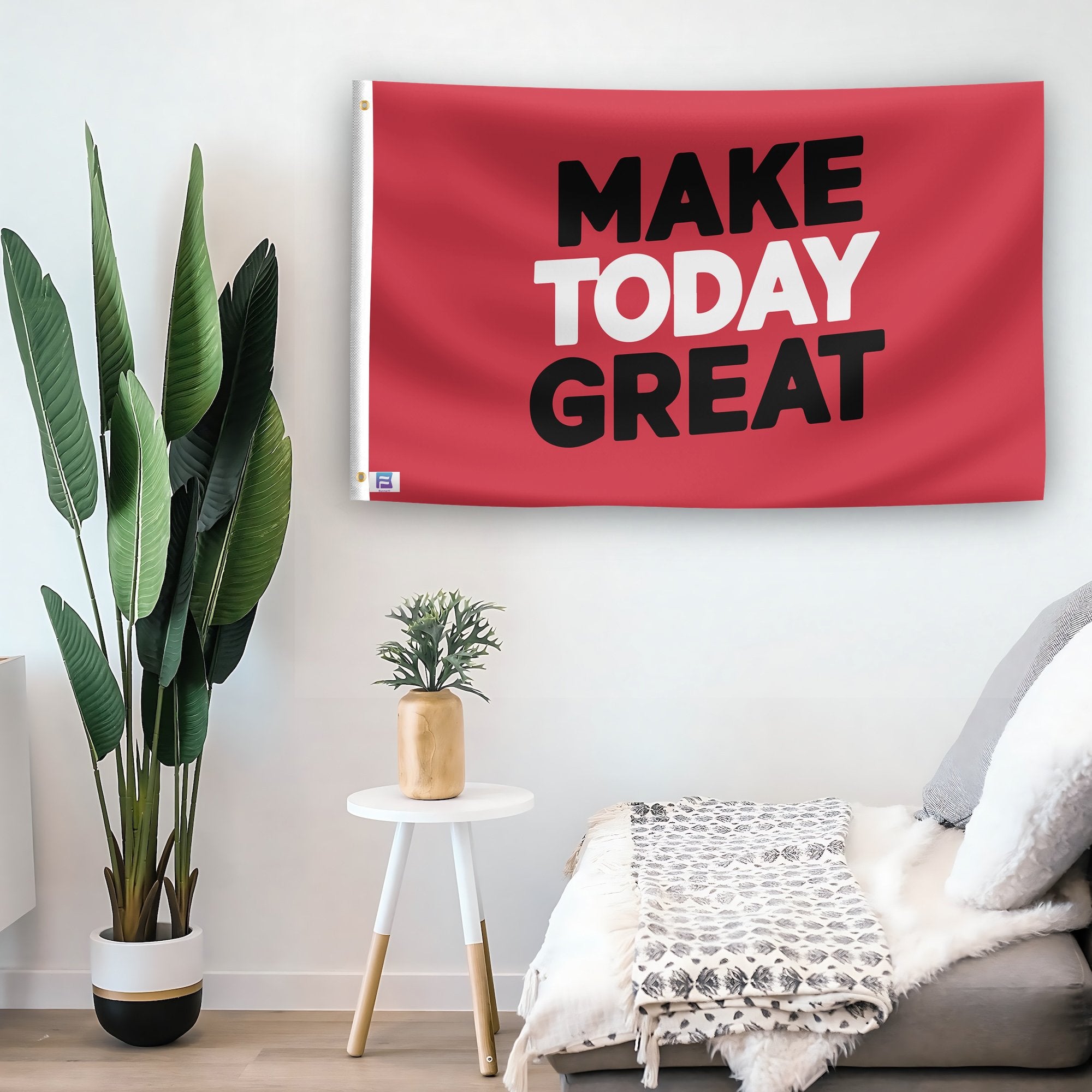 In a home setting, a flag with the saying "Make Today Great" is mounted on a white wall by a side table.