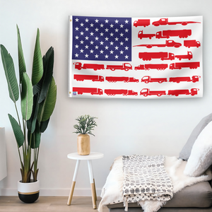 In a home setting, an american flag with the theme "Truck Stripes American" is mounted on a white wall by a side table.