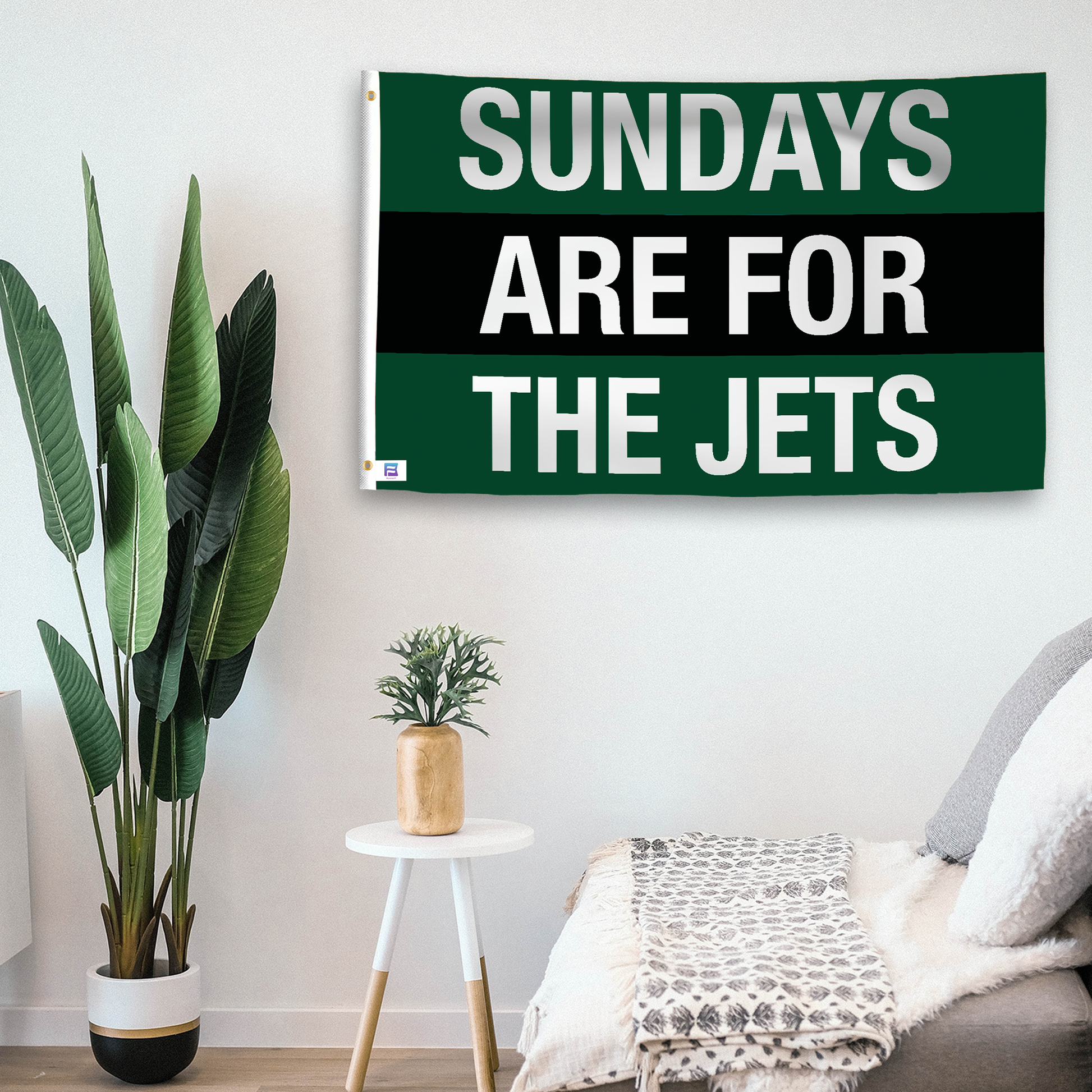 In a home setting, a flag with the saying "https://www.dropbox.com/scl/fi/p9uf4na7cej44l9e0ekrs/sundays-are-for-the-jets_room.png?rlkey=g4rk96kfgun87lv1keiuc8ob5&raw=1" is mounted on a white wall by a side table.