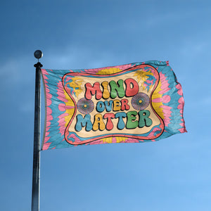 A flag with the saying "Mind Over Matter" displayed on a high pole, with a tie dye style color scheme.