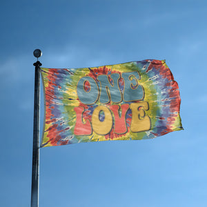 A flag with the saying "One Love" displayed on a high pole, with a tie dye style color scheme.