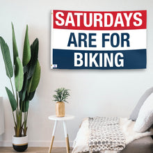 Load image into Gallery viewer, In a home setting, a flag with the saying &quot;https://www.dropbox.com/scl/fi/hurux88lqbk8sc8aapfz5/saturdays-are-for-biking_room.png?rlkey=tw9lpn870n8uqwvekyj99hpkf&amp;raw=1&quot; is mounted on a white wall by a side table.
