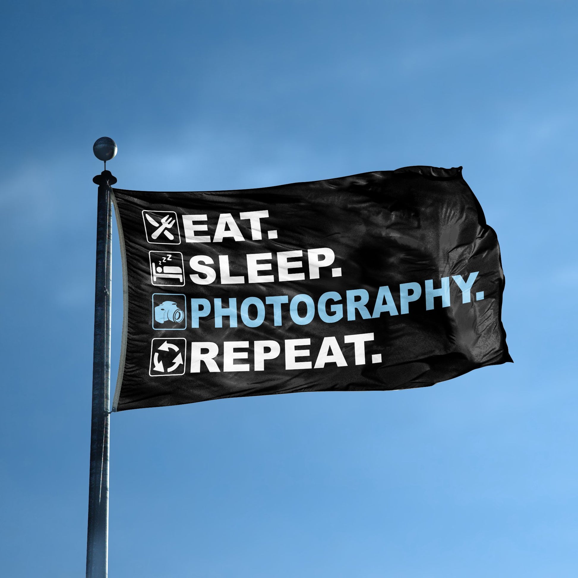 A flag with the saying "Eat Sleep Photography Repeat" displayed on a high pole, with a black, white and themed color scheme.