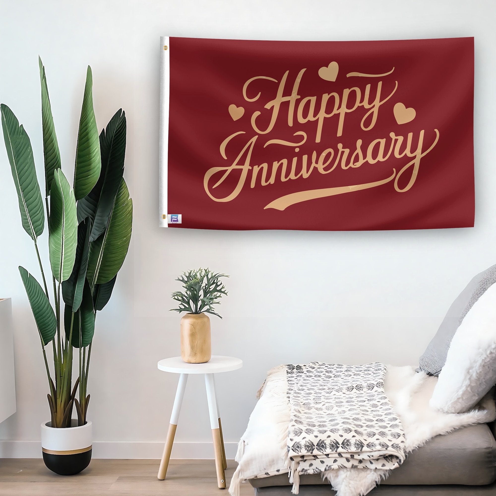 In a home setting, a flag with the saying "Happy Anniversary" is mounted on a white wall by a side table.