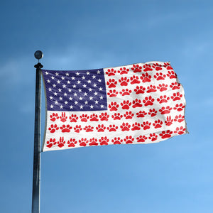 An american flag with the red stripes changed to match the theme "Paw Prints Stripes American" displayed on a high pole.