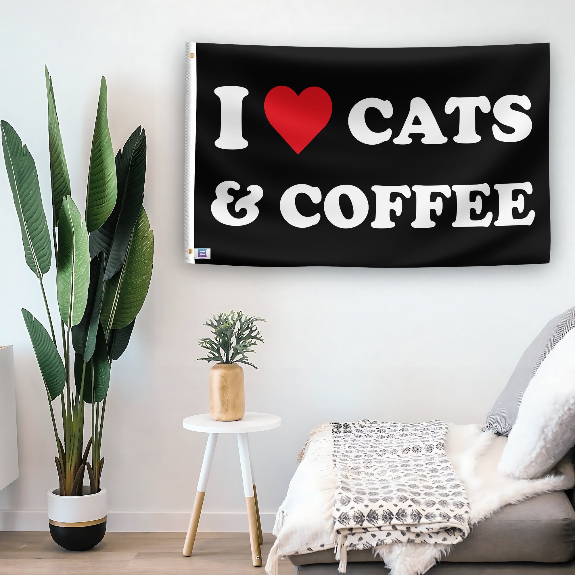 In a home setting, a flag with the saying "I Love Cats And Coffee" is mounted on a white wall by a side table.