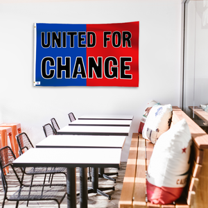 A political flag in royal blue and crimson red with a political statement on a wall in a cafe setting.