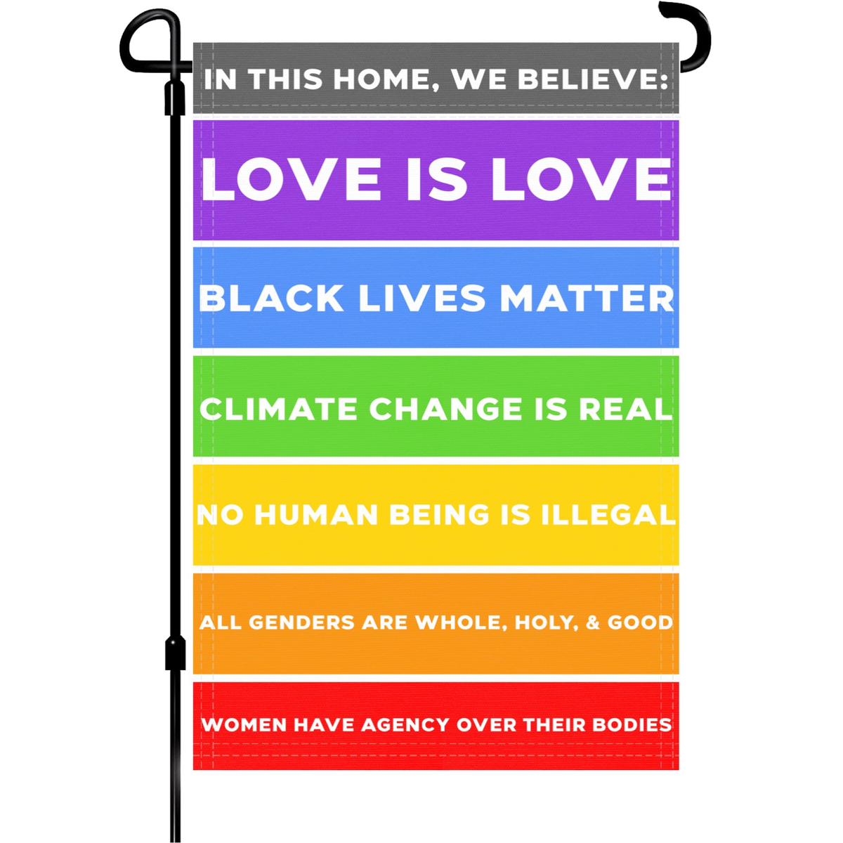 In This Home We Believe Garden Flag with colorful stripes displaying Love Is Love, Black Lives Matter, Climate Change Is Real, and other social justice messages.
