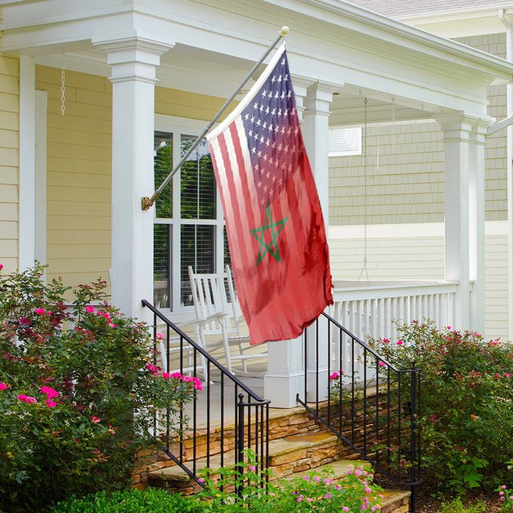 A hybrid flag featuring elements of the American flag and the Moroccan flag, with a red background and a green star on a porch flagpole.