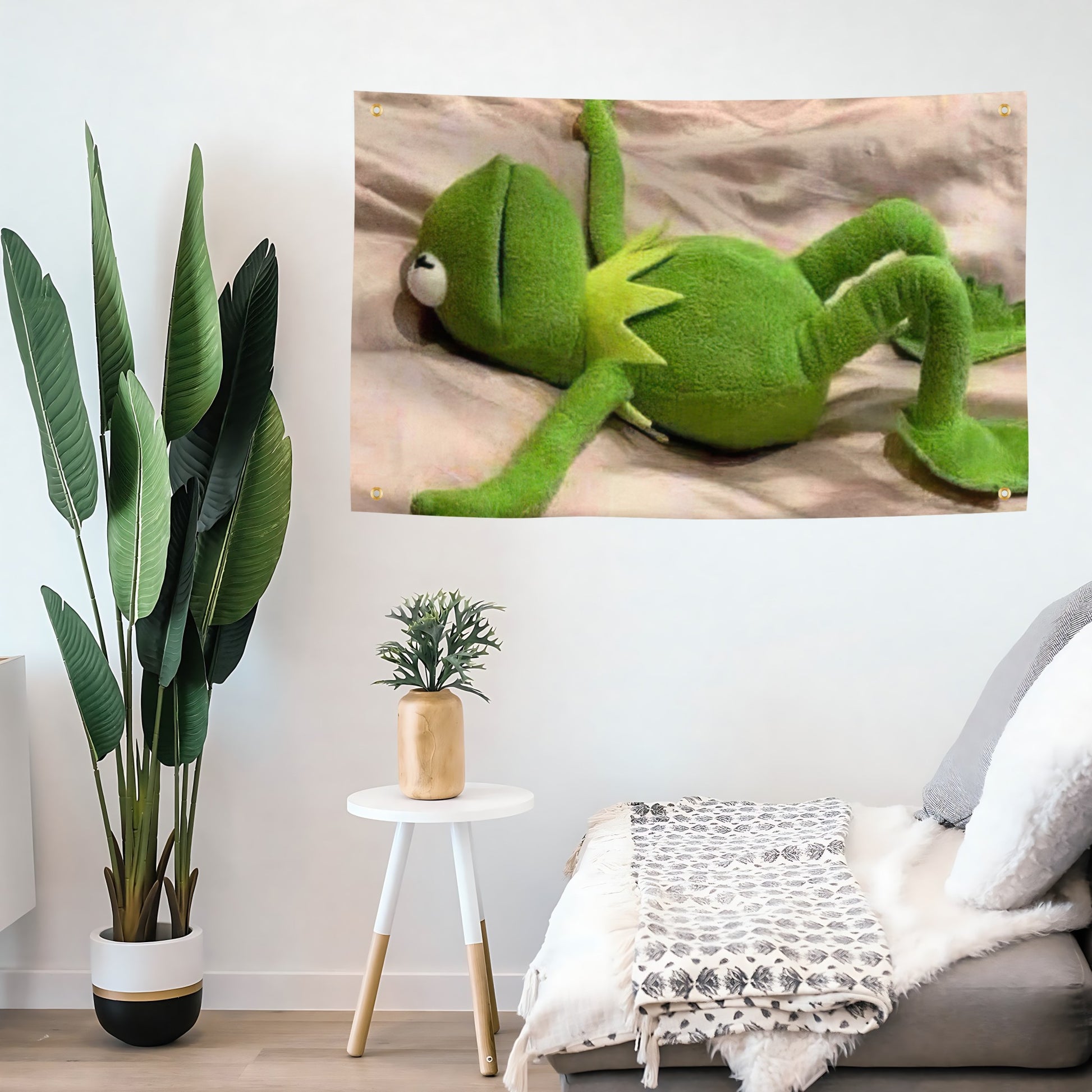 A funny meme flag banner with Kermit the Frog laying down on a sheet looking defeated, hanging on a living room wall.