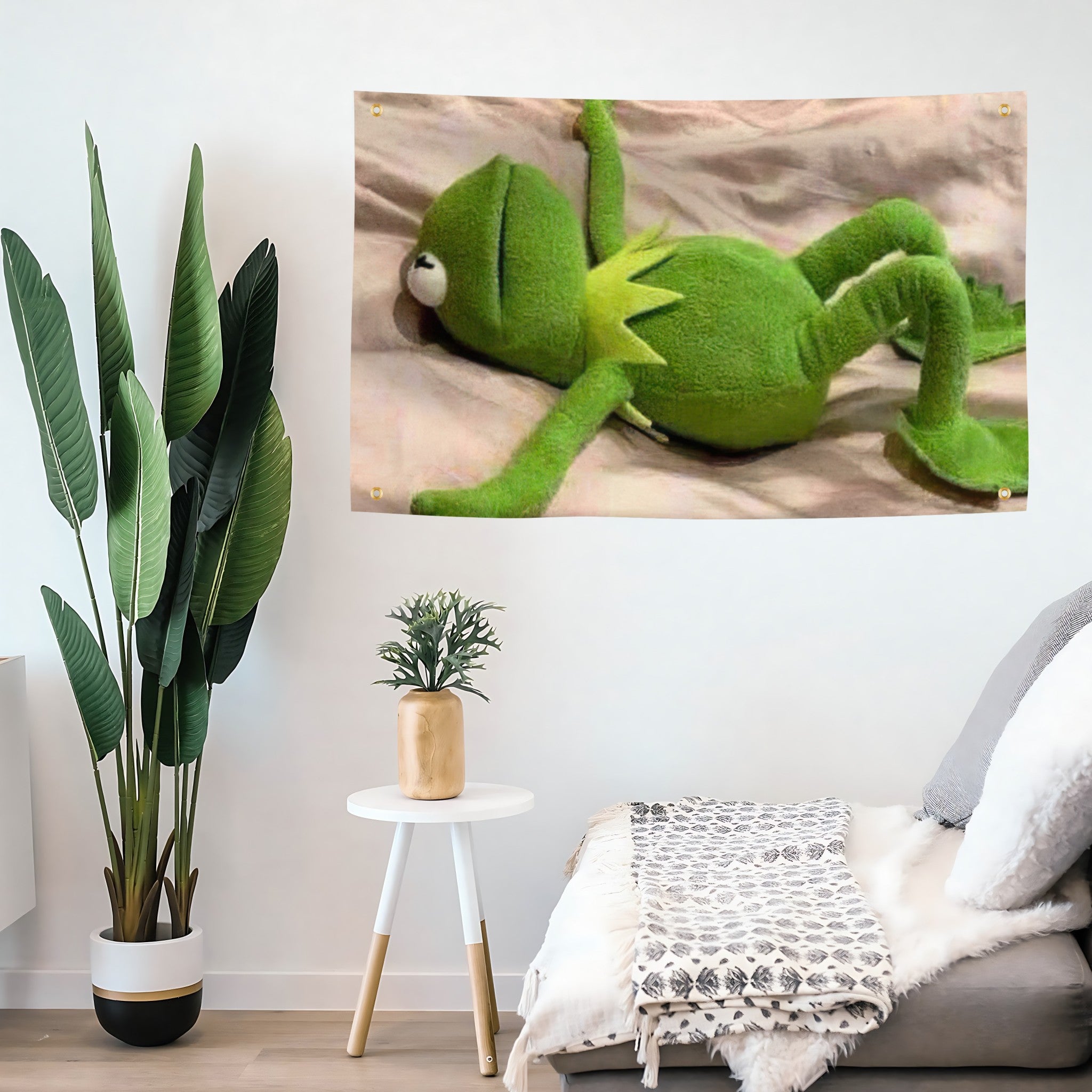 A funny meme flag banner with Kermit the Frog laying down on a sheet looking defeated, hanging on a living room wall.