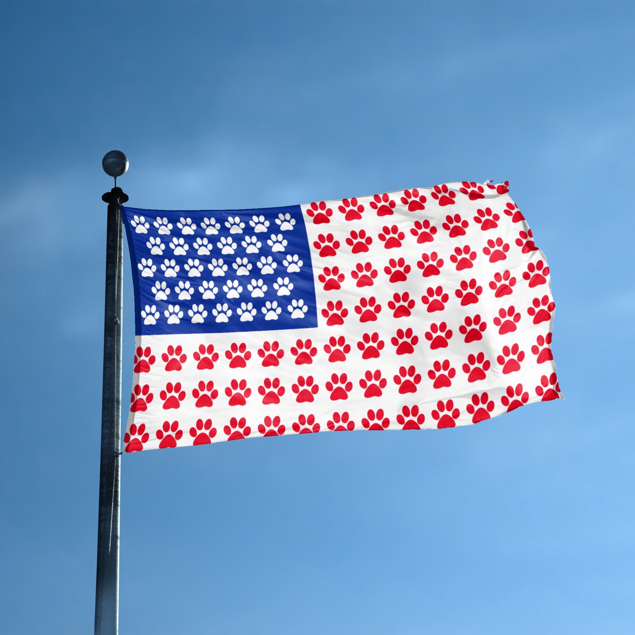 A flag with the theme "Paw Print American" displayed on a tall flag pole and blue skies.