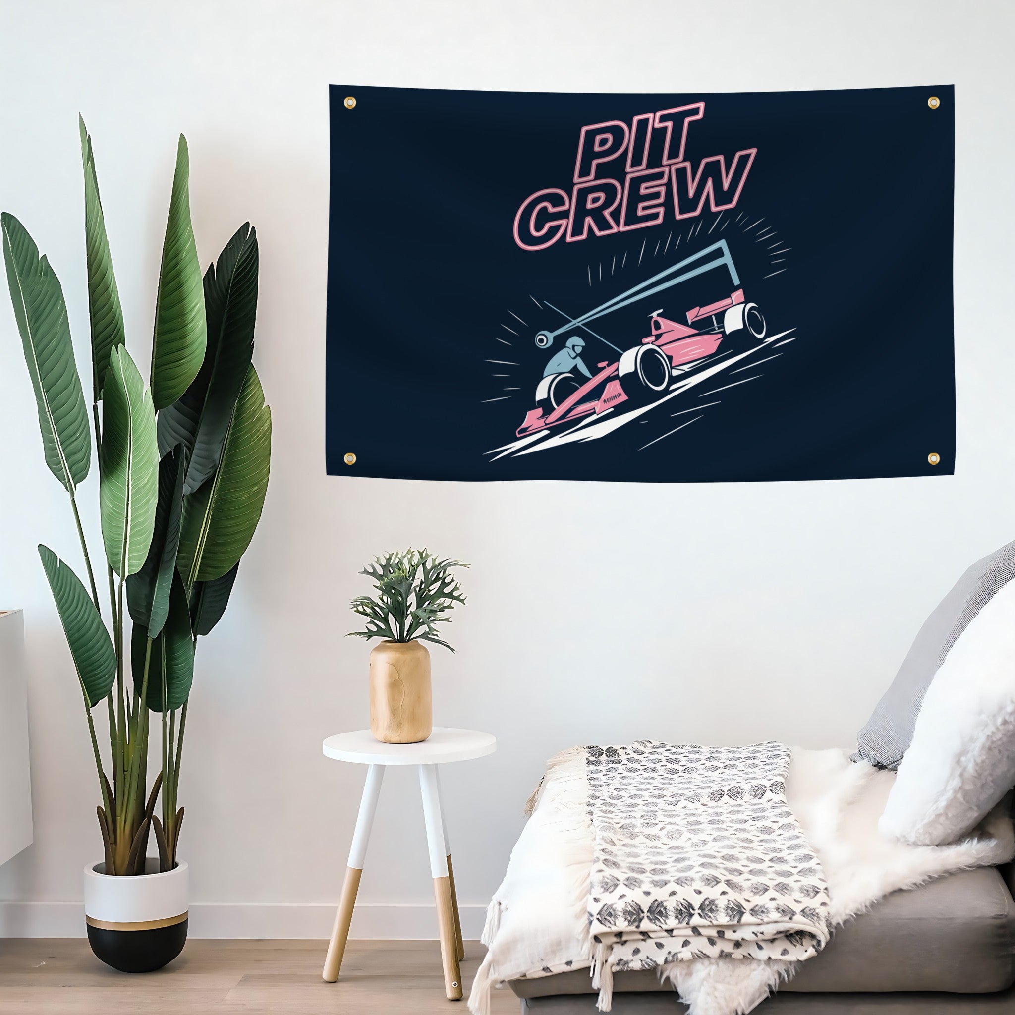 Pit Crew flag banner hanging on a wall above a sofa with decorative plants.