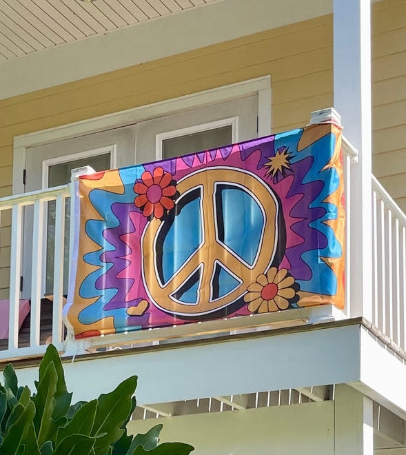 Colorful peace sign flag on a balcony with a house in the background