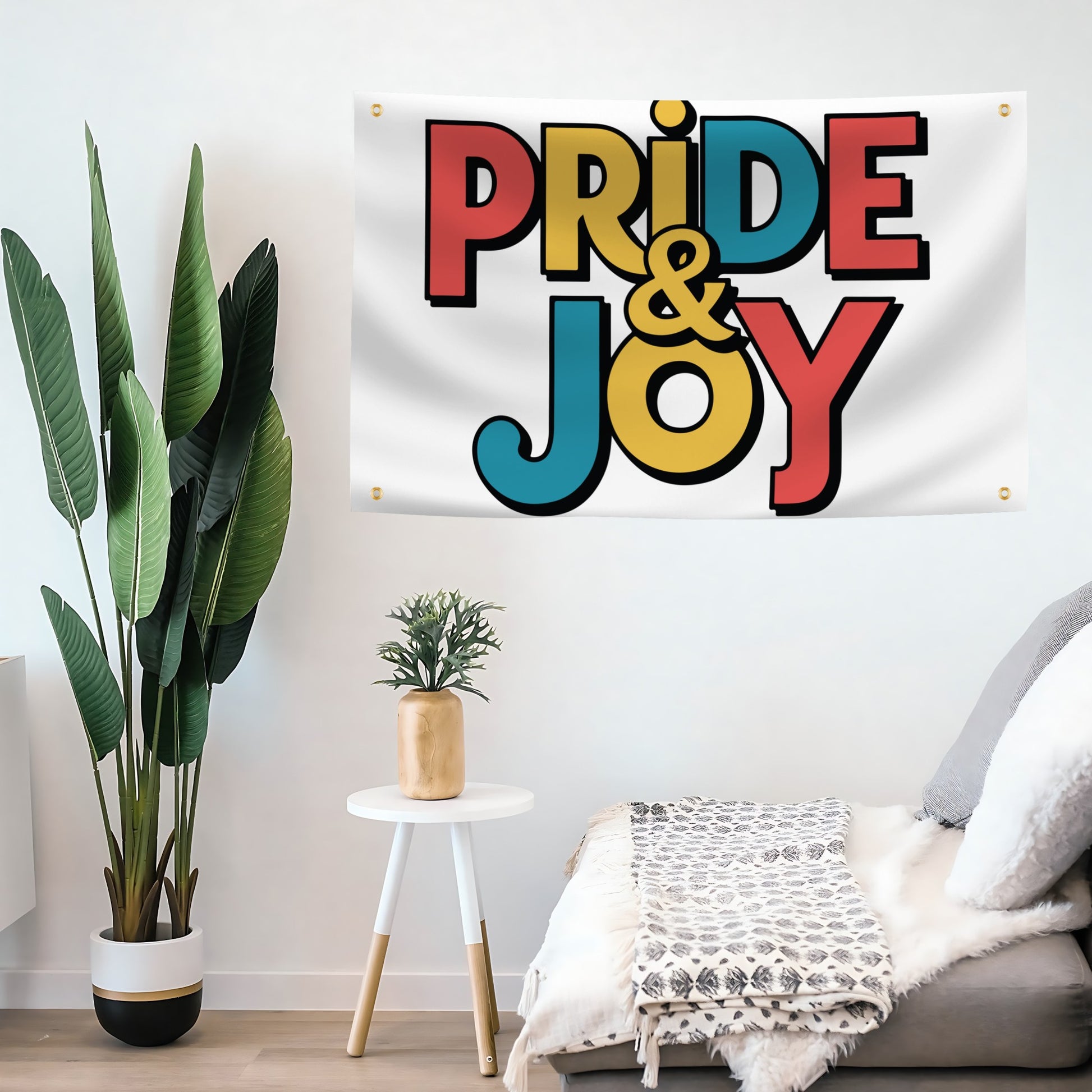 A flag banner with a white background featuring the text 'PRIDE & JOY' in colorful, bold lettering on a living room wall.
