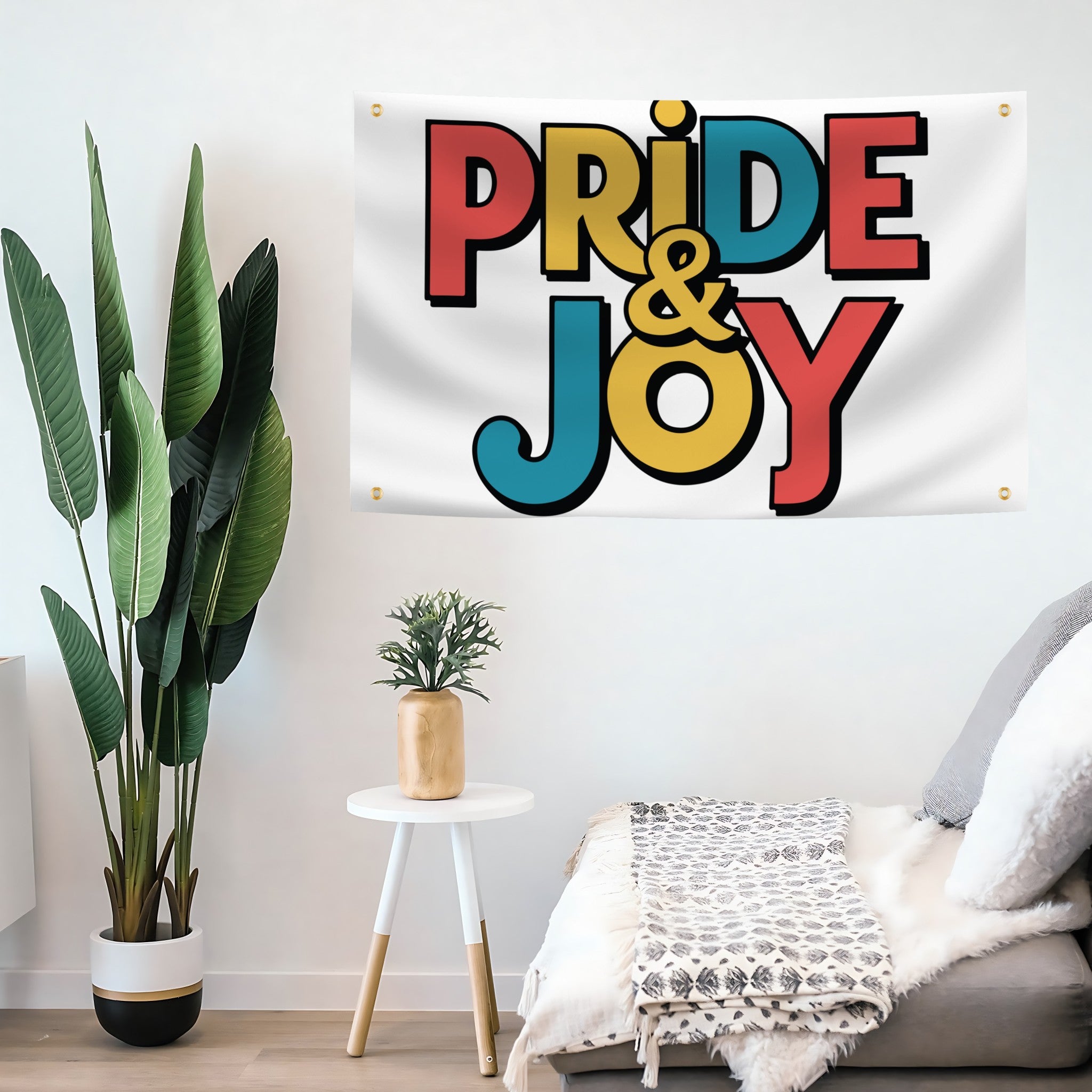 A flag banner with a white background featuring the text 'PRIDE & JOY' in colorful, bold lettering on a living room wall.