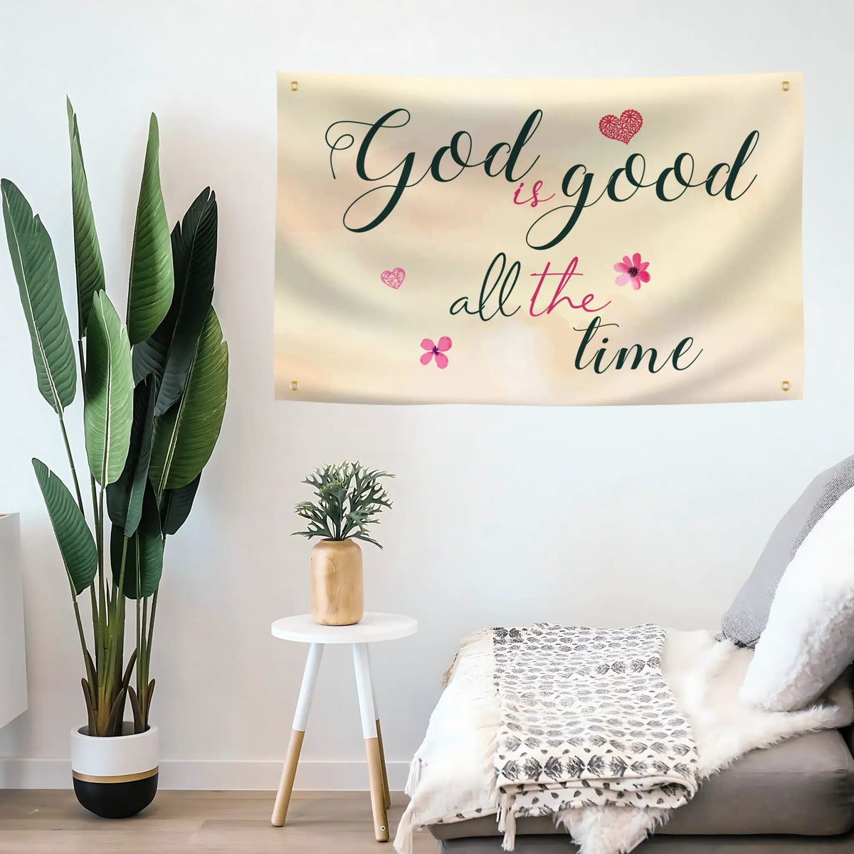God is Good All the Time Flag, a Bannerfi house flag in beige with dark script and pink hearts, hung on wall.
