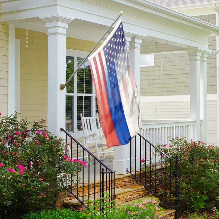 A hybrid flag featuring elements of the Russian and American flags, with a stars and stripes pattern hanging on a porch.
