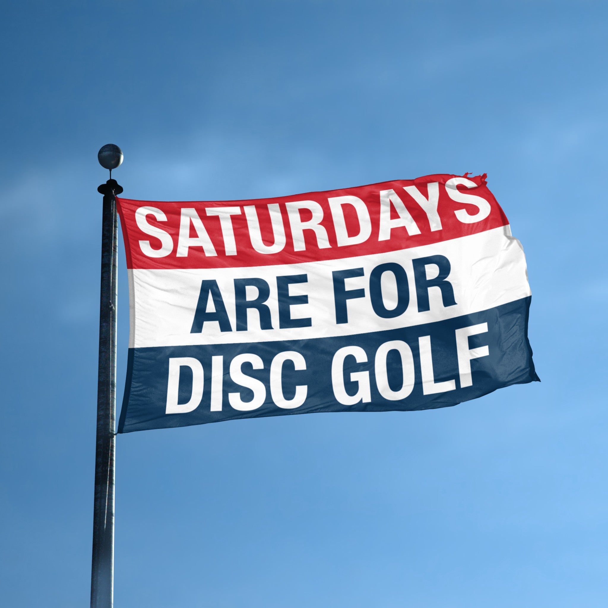 Flag with 'Saturdays are for Disc Golf' text against a blue sky