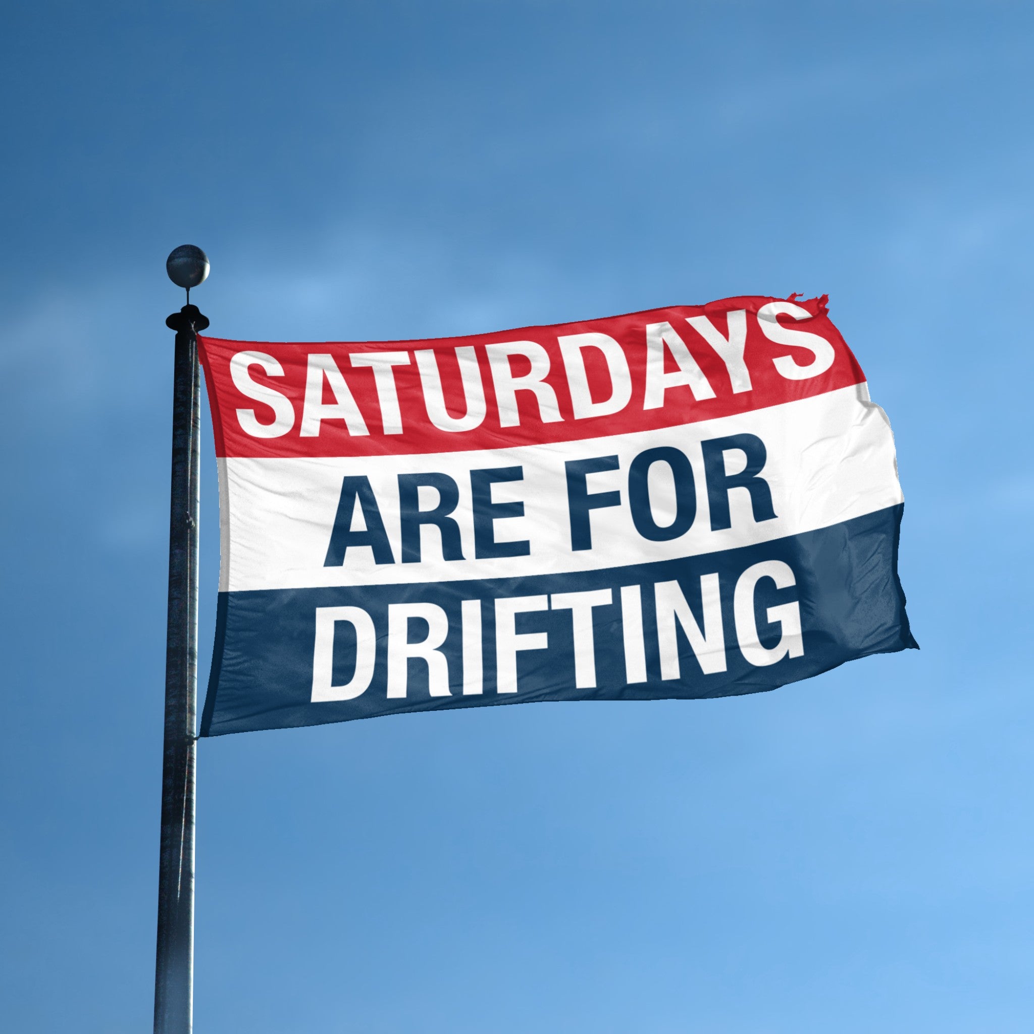 Flag with 'Saturdays are for Drifting' text against a blue sky