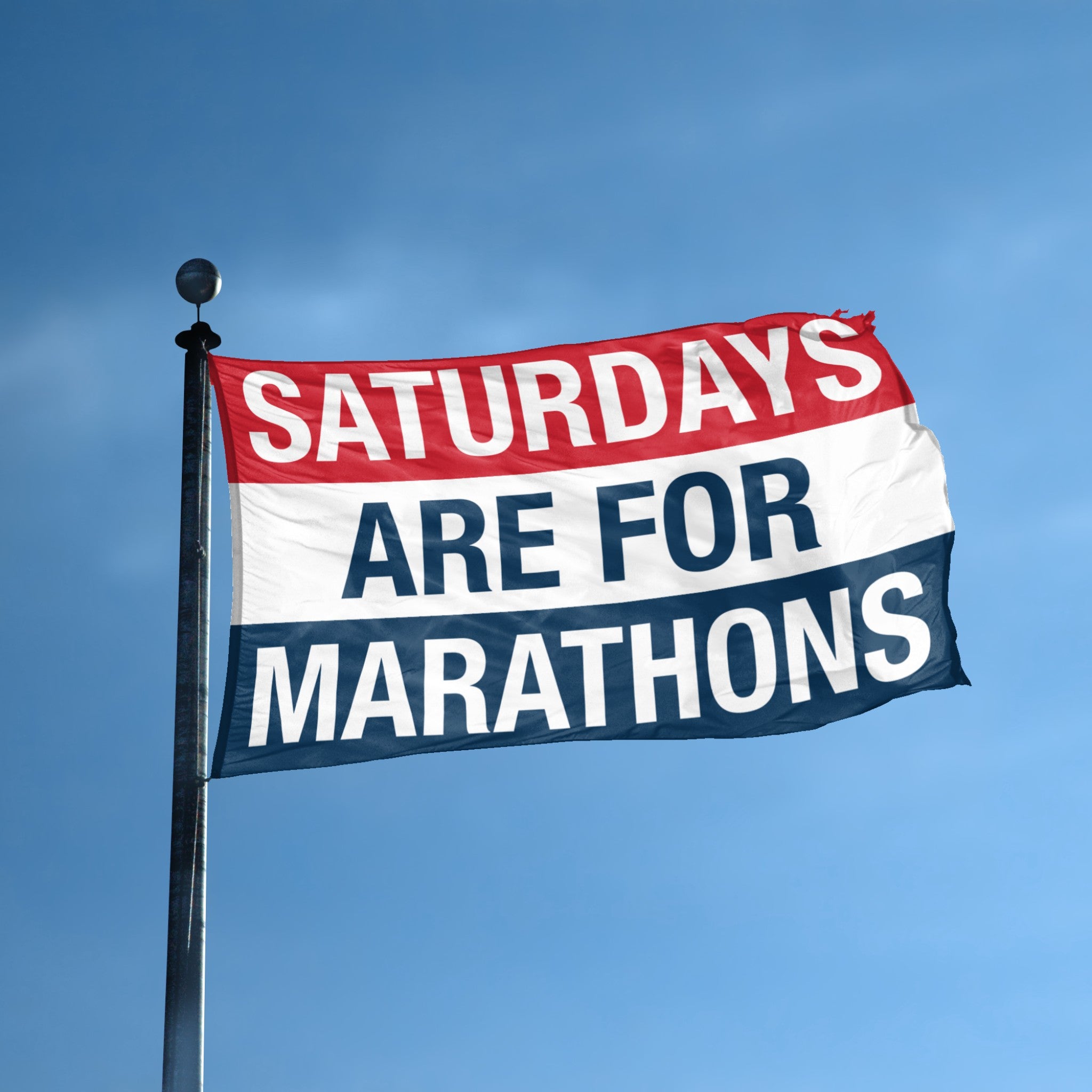 Flag with 'Saturdays are for Marathons' text against a blue sky