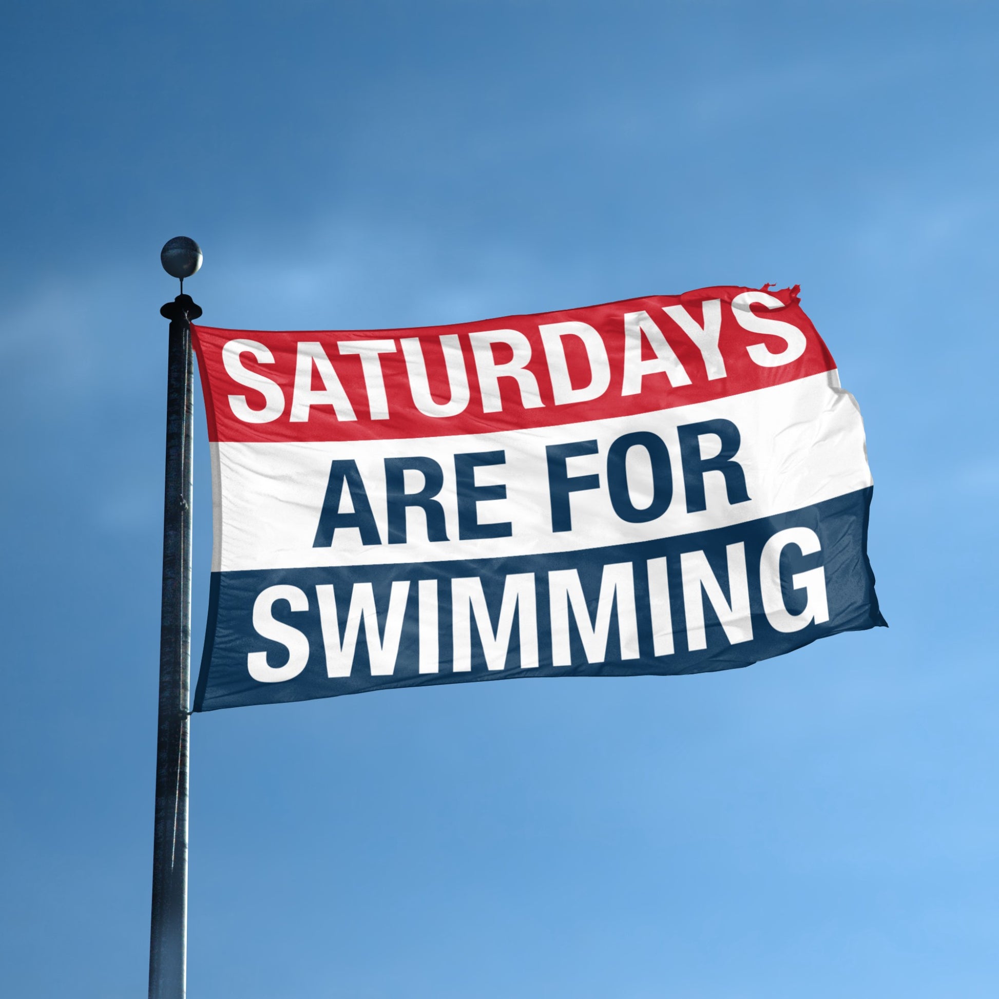 Flag with 'Saturdays are for Swimming' text against a blue sky