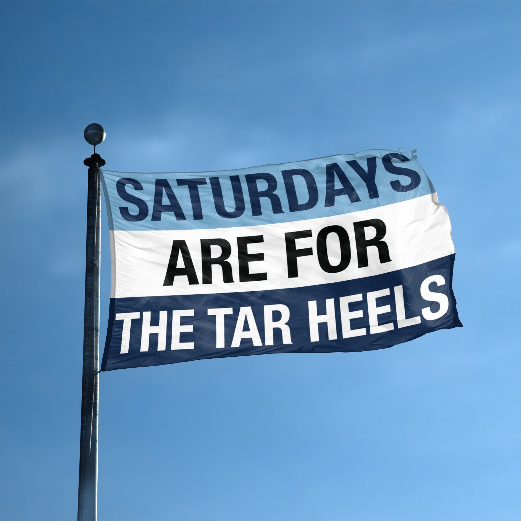 A flag on a flagpole with a blue and white color scheme, featuring the text 'SATURDAYS ARE FOR THE TAR HEELS' in bold letters.