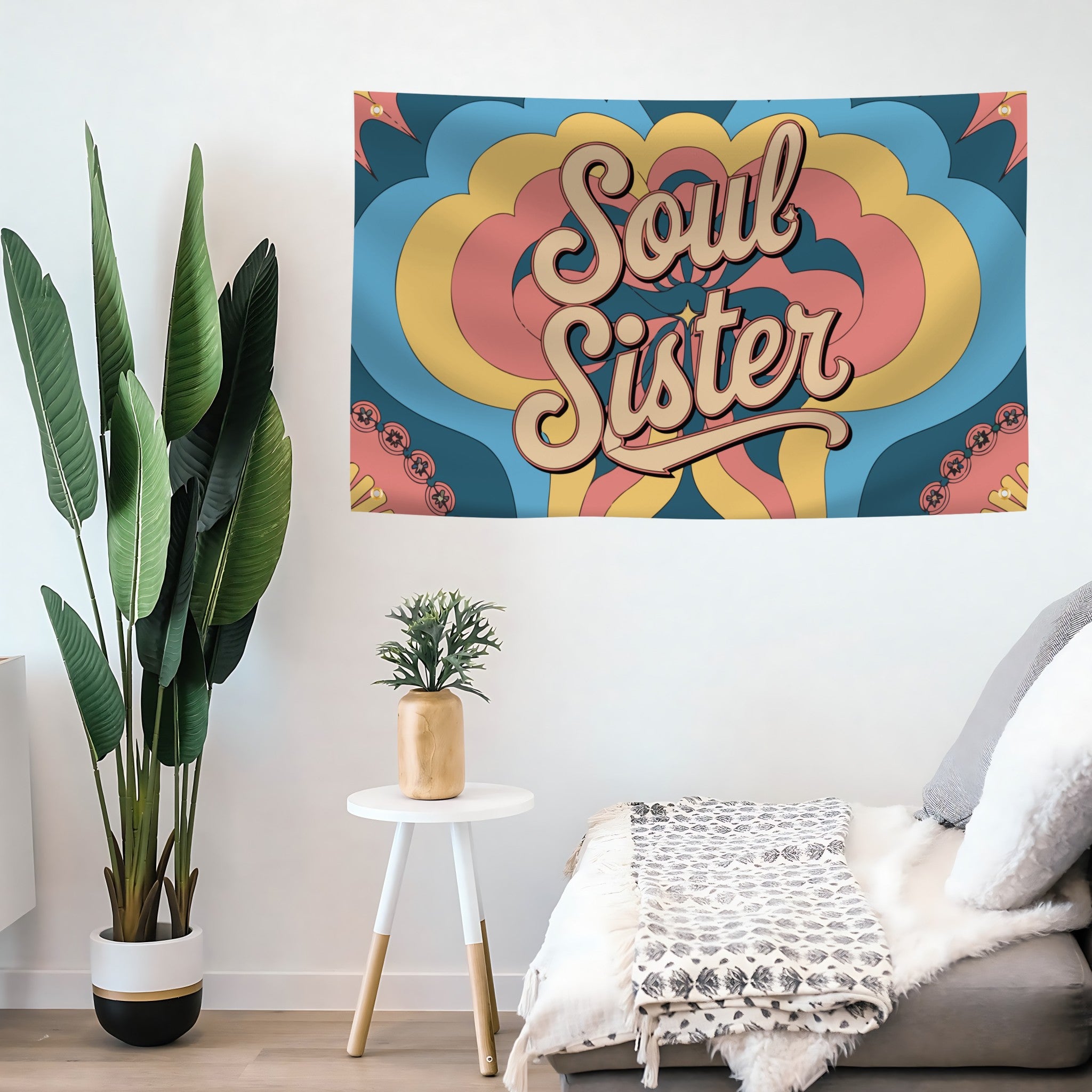 Colorful 'Soul Sister' flag banner on a wall with plants and a chair in the foreground.