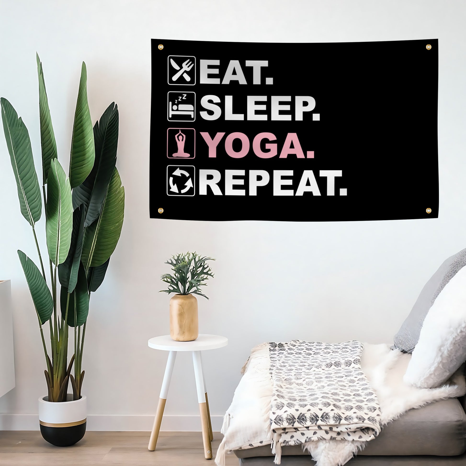 A flag banner with the text "Eat Sleep Yoga Repeat", with a black, white and pink color scheme mounted on a wall.