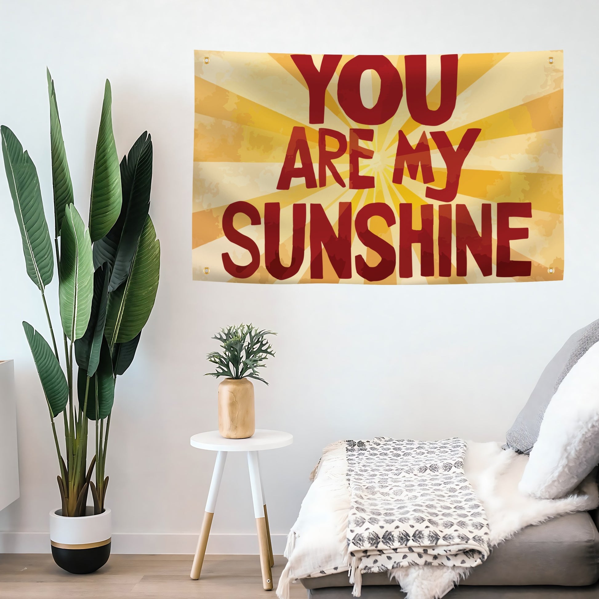 Living room with 'You Are My Sunshine' flag banner on the wall, plants, and a small table.