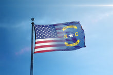 Load image into Gallery viewer, the flag of the state of north carolina flies high in the blue sky
