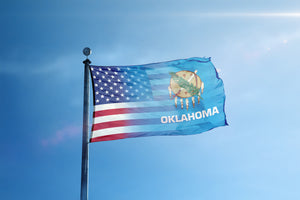 the flag of the state of oklahoma flies high in the blue sky
