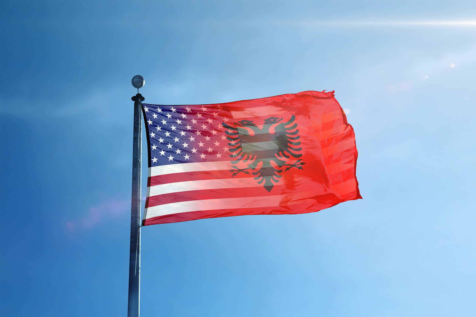 a flag flying in the wind on a sunny day